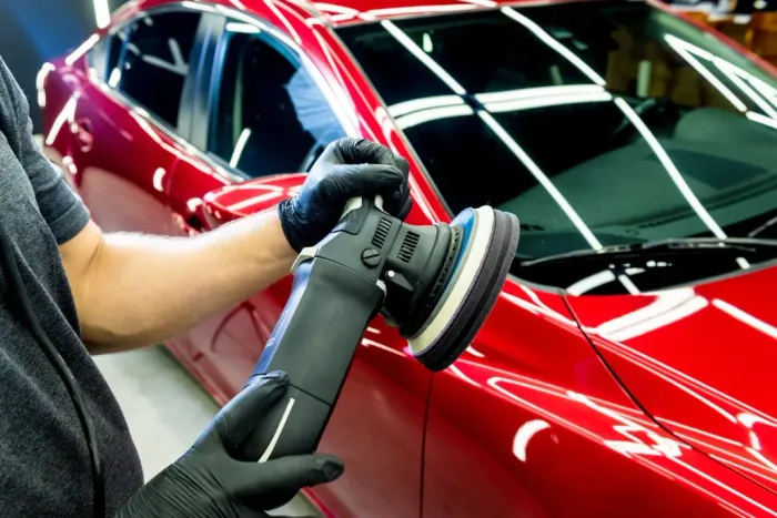 Caristic technician polishing a red car before ceramic coating
