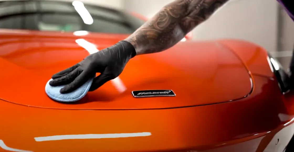 Detailer applying paint protection film to an orange car